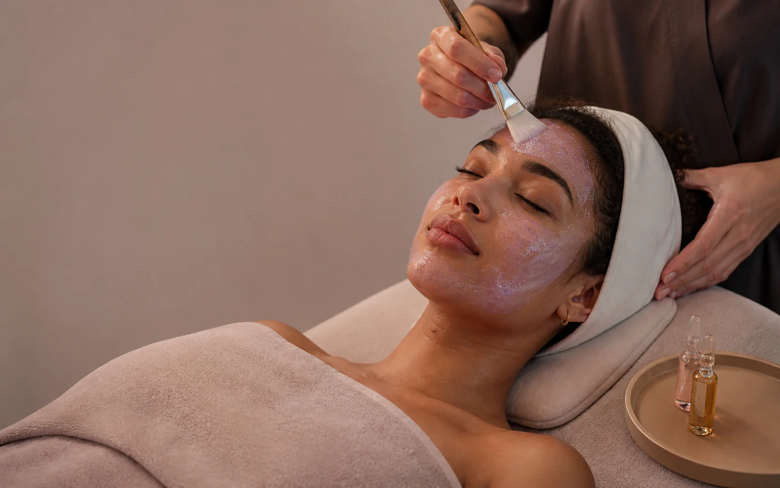 Esthetician applying a luminous lavender gel mask during a Glow4Facial ritual